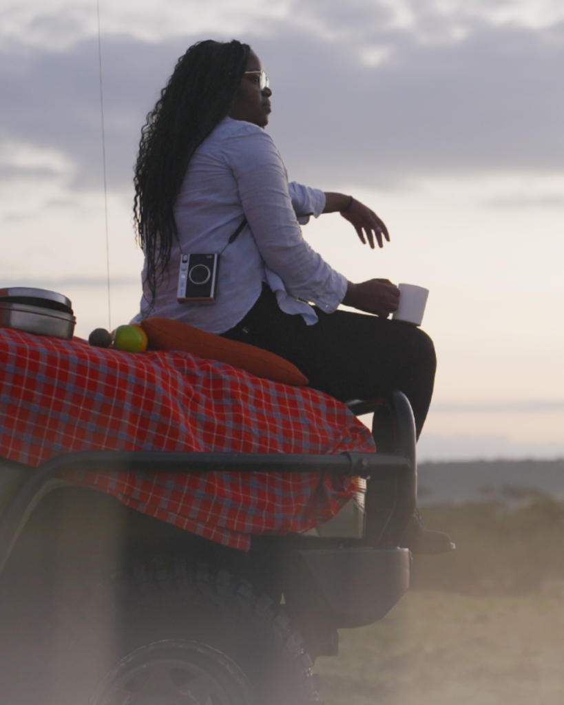 Tanzanian poet Helen Bulugu sat on the front of a safari vehicle watching the sunset