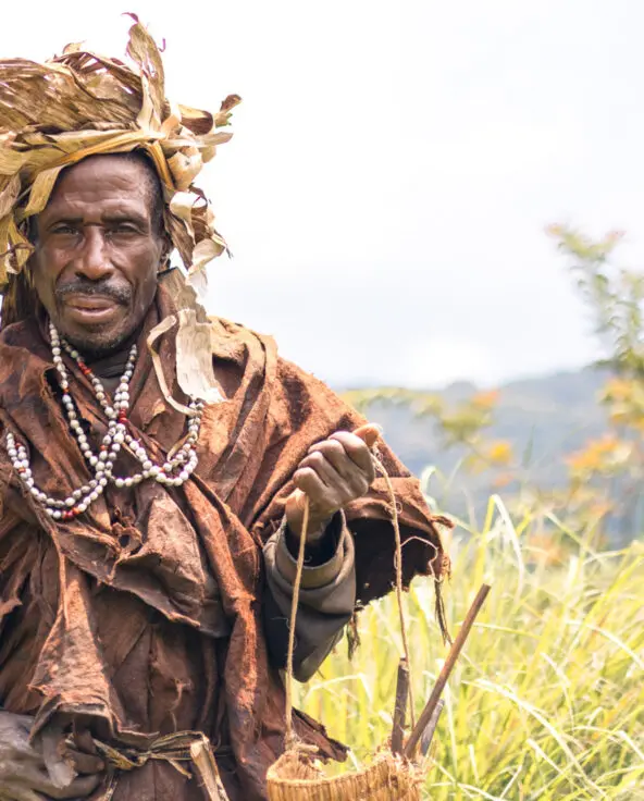 Local tribesman facing the camera with the Bwindi Impenetrable Forest behind him, Erebero Hills, Uganda