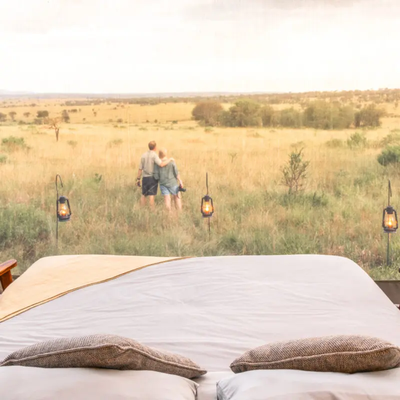Serengeti National Park, lanterns outside star gazing tent with couple in the distance