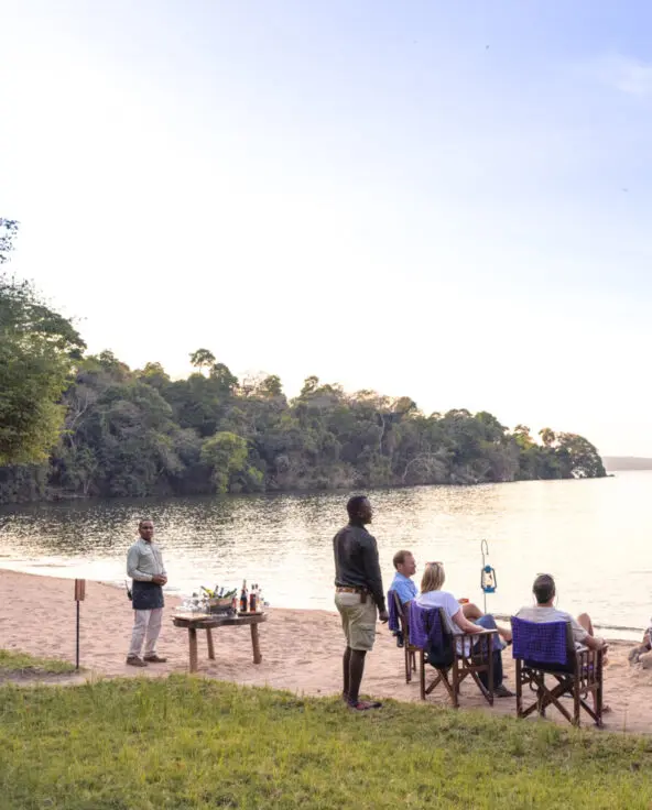 Lake Victoria, shore, guests by the fire with guide and waiter, drinks, chairs, sand