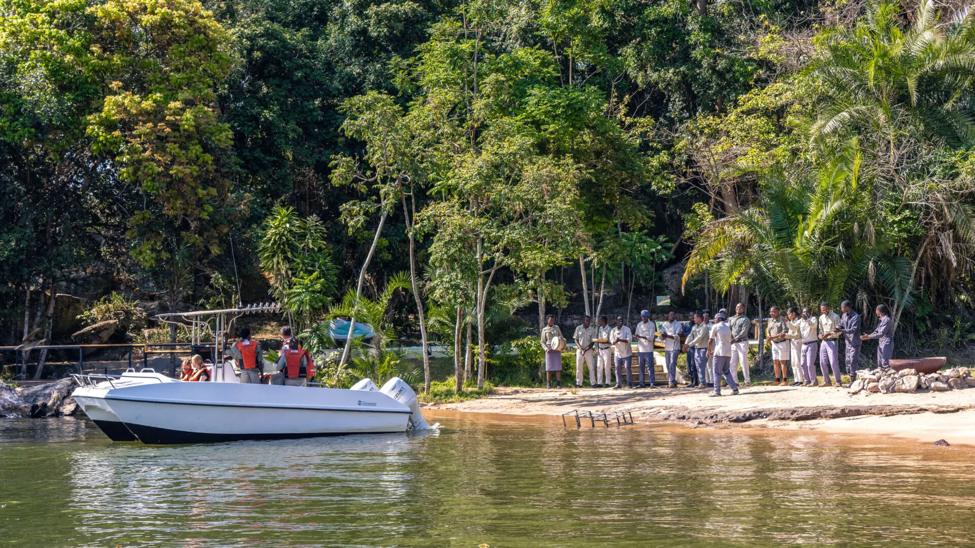 Staff standing on the banks of Lake Victoria as guests head out on a boating safari_Tanzania