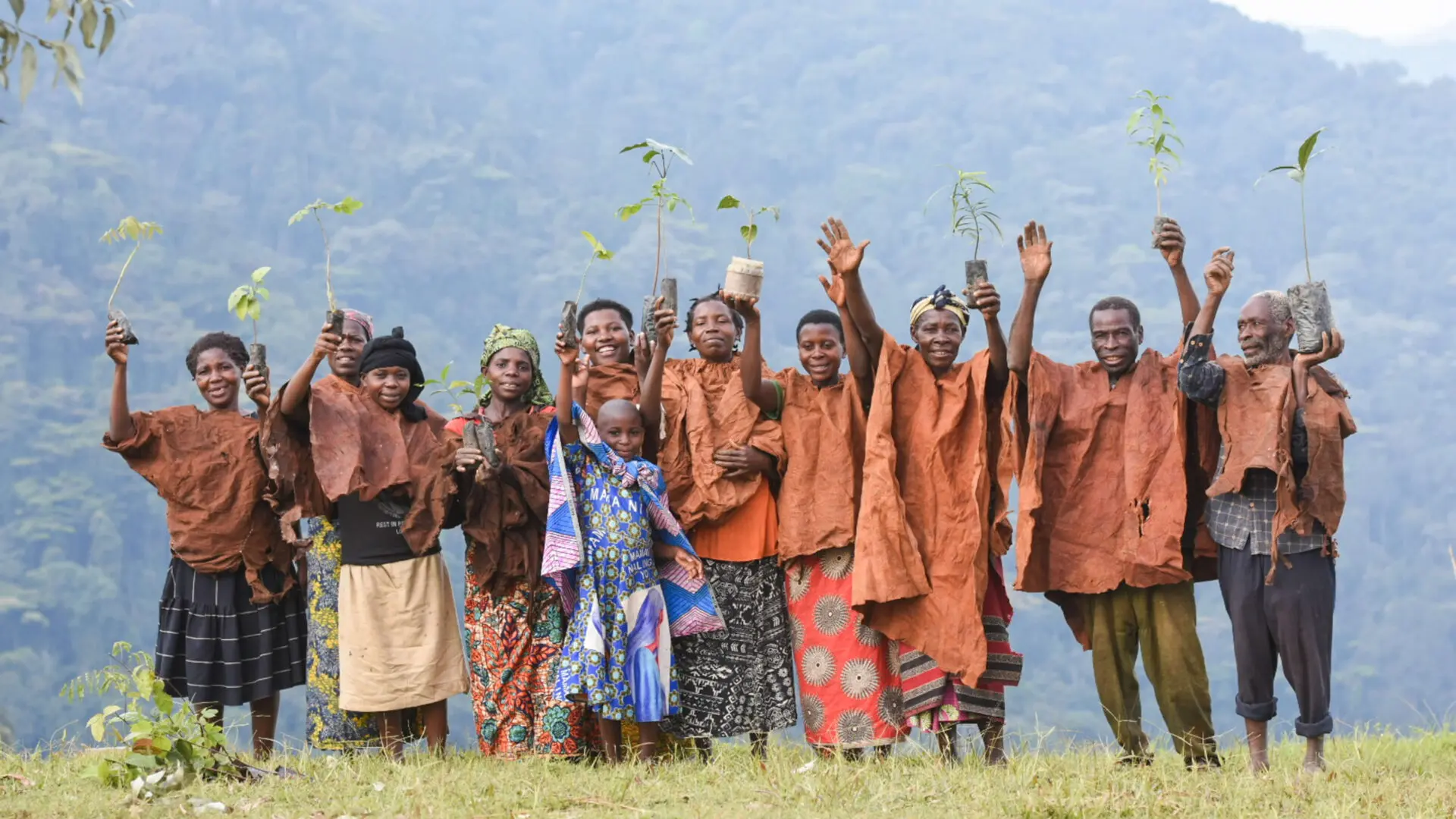 group of batwa people smiling and waving, bwindi, uganda