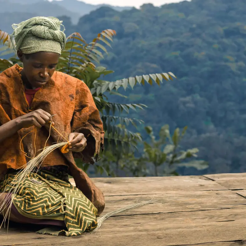 batwa lady sat weaving in bwindi impenetrable forest uganda