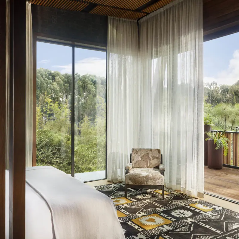 One Only Gorilla's Nest Guest suite interior with balcony and view of the forest, double bed