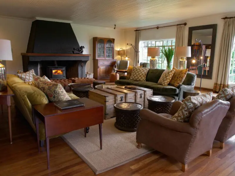 Wilderness Sabyinyo lounge area interior with couches, fireplace and garden view