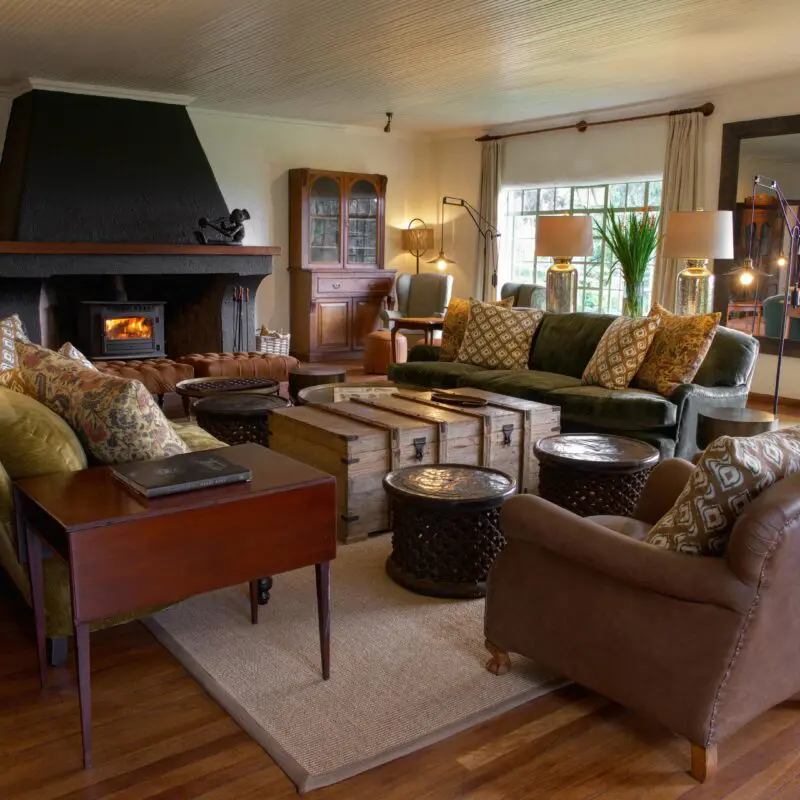 Wilderness Sabyinyo lounge area interior with couches, fireplace and garden view