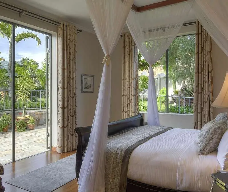 Bishop's House Guest bedroom interior with door leading out to patio with garden view