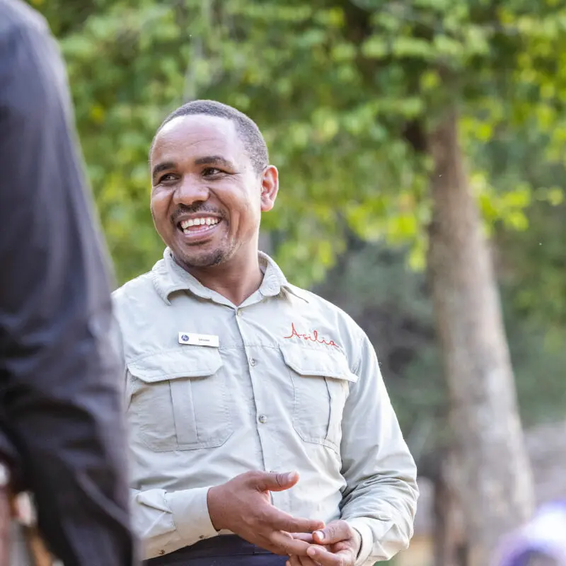 male staff member laughing with a guest on safari - asilia africa