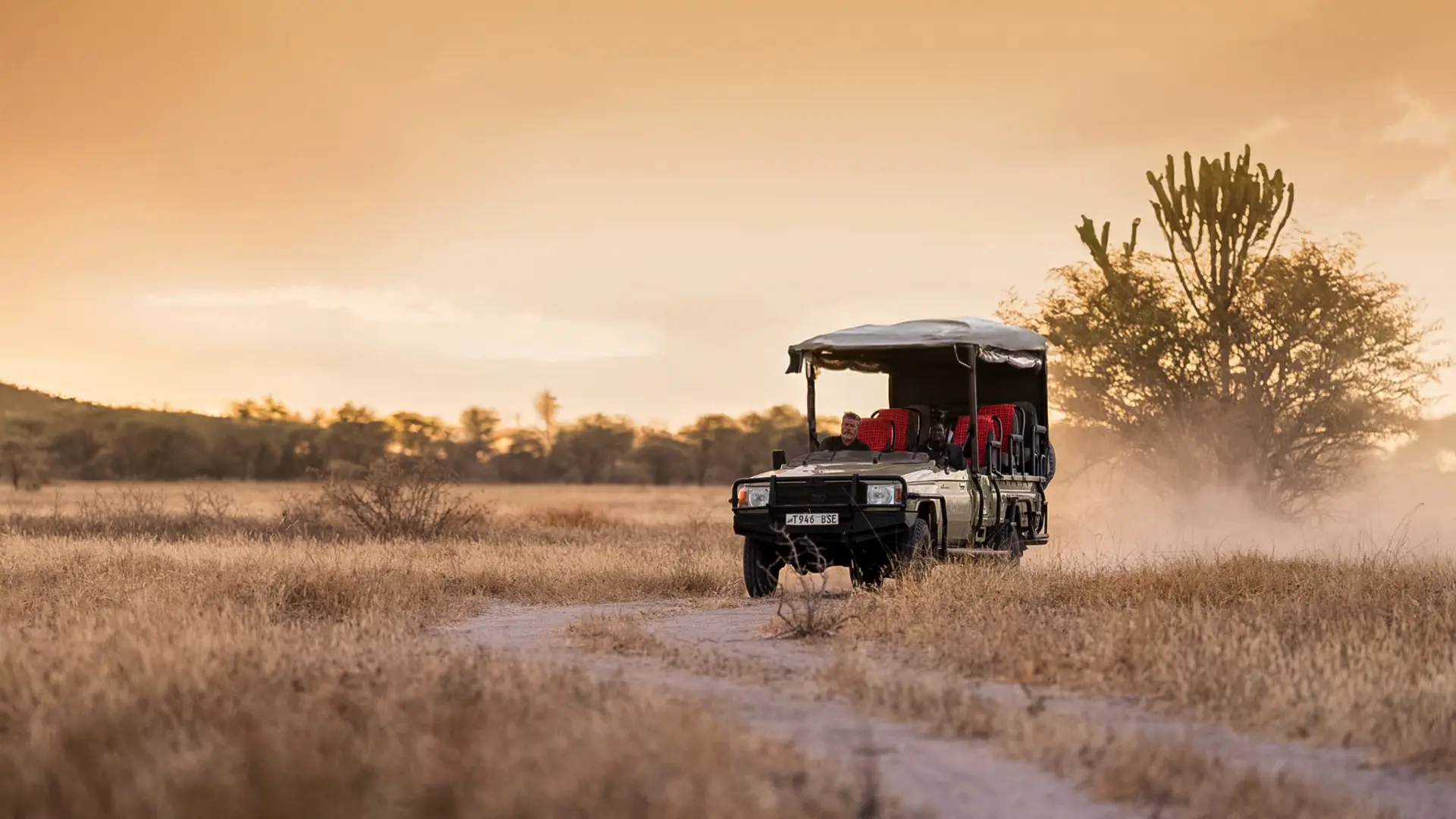 an asilia africa safari vehicle driving along the dusty track at dusk in southern tanzania