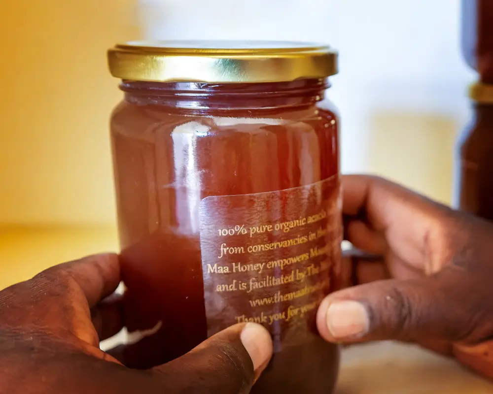 Bottles of honey being labelled by hand at The Maa Trust, Kenya