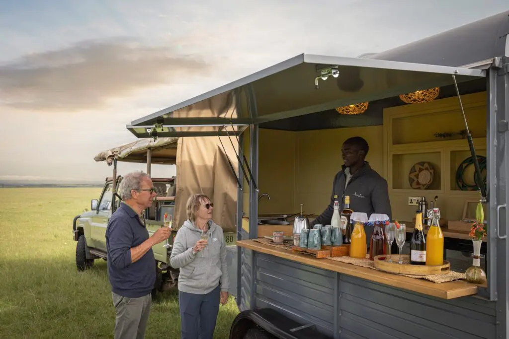 An elderly couple enjoys a sundowner on safari