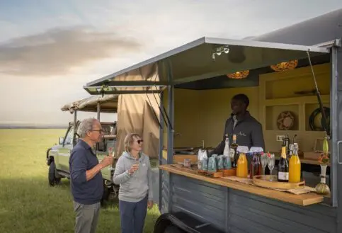 An elderly couple enjoys a sundowner on safari