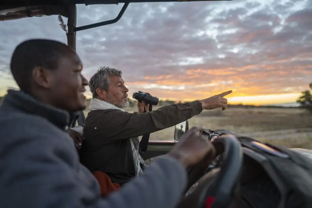 A guide and a guest on a drive at sunset
