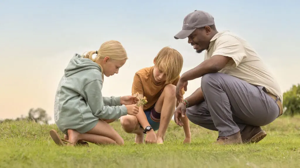 Two children being taught about the flora in the Ol Pejeta Conservancy by one of the Asilia guides