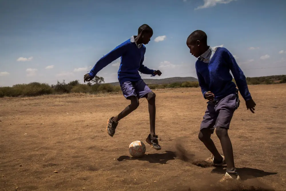 School children enjoy a game of football, Kenya.