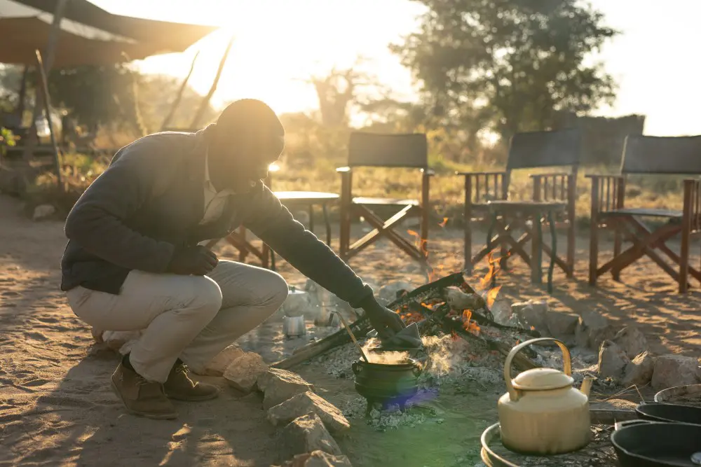 A staff member prepares breakfast over the open fire, Usangu Expedition Camp, Tanzania.