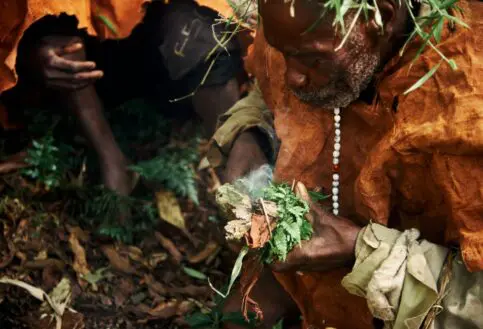 A Batwa elder coaxes a fire to life in Bwindi Forest, Uganda