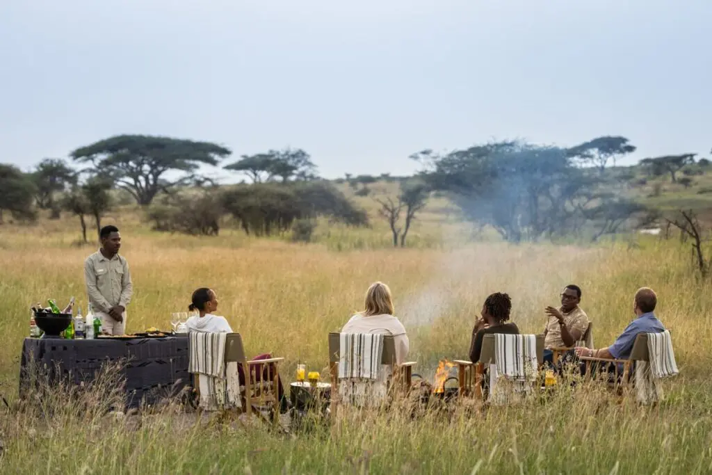 A group gathers at the fireside after a day on safari
