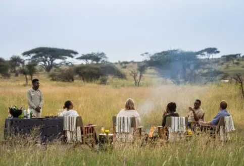A group gathers at the fireside after a day on safari