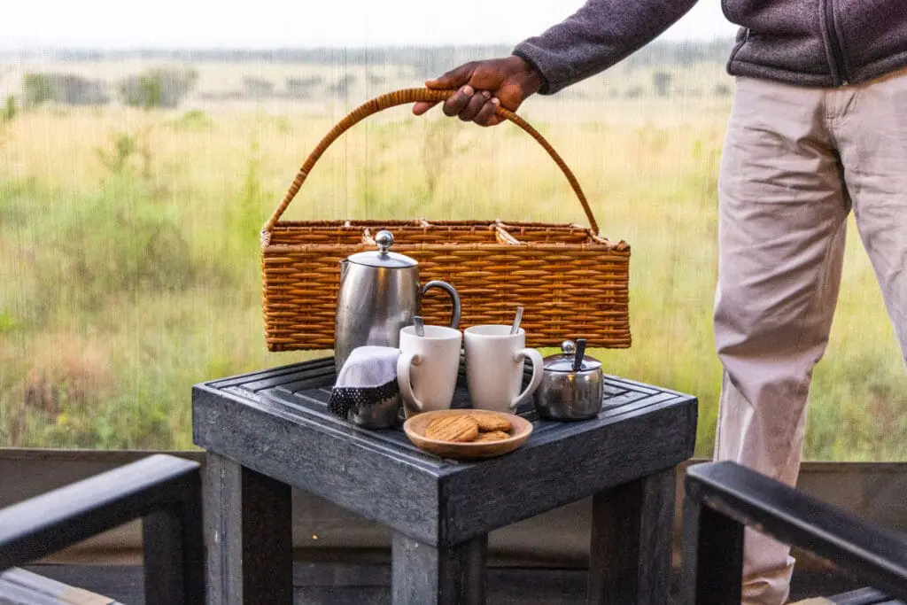 Staff at Olakira Migration Camp in Tanzania delivering coffee to guest tents. 