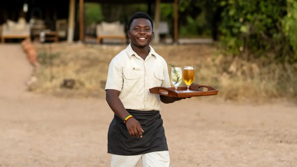 A waiter with drinks, Kokoko Camp, Ruaha National Park, Tanzania.