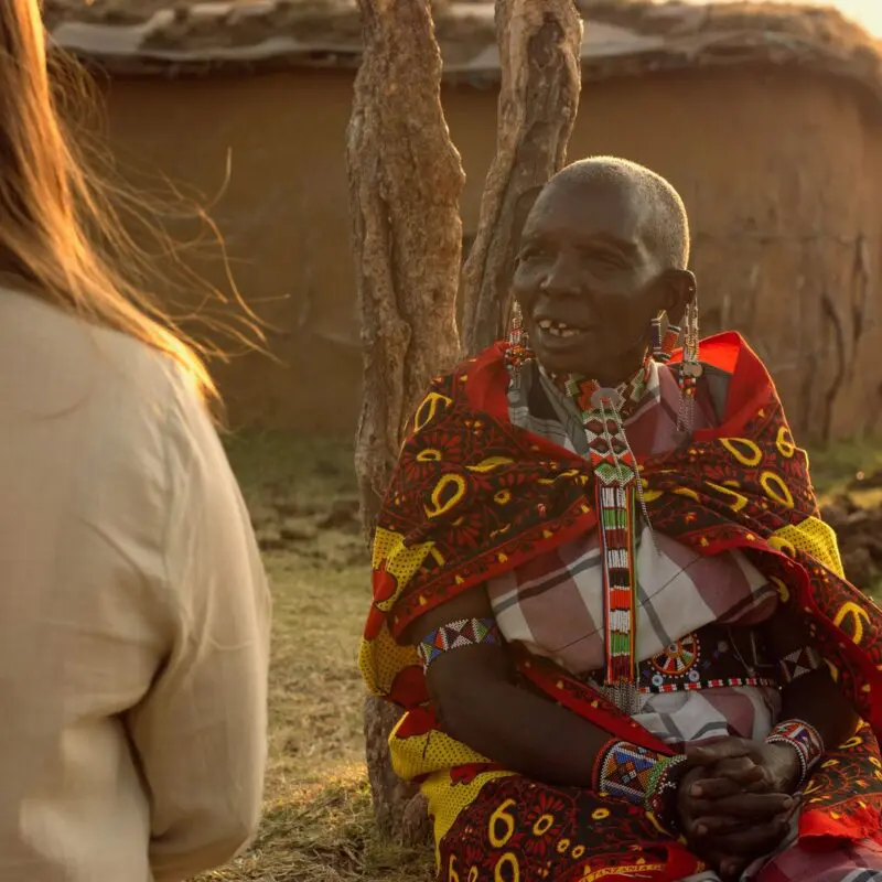 Asilia guest and Maasai elder sharing conversation at their village in The Highlands.