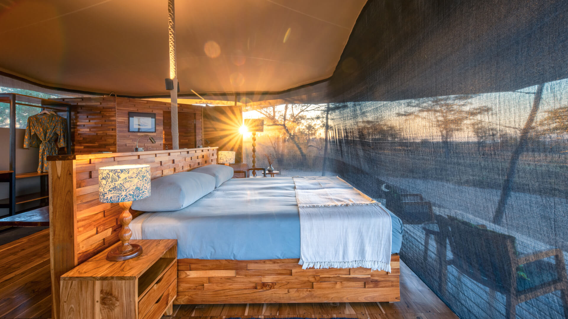 A tent interior showing a double bed and the view through the net sides