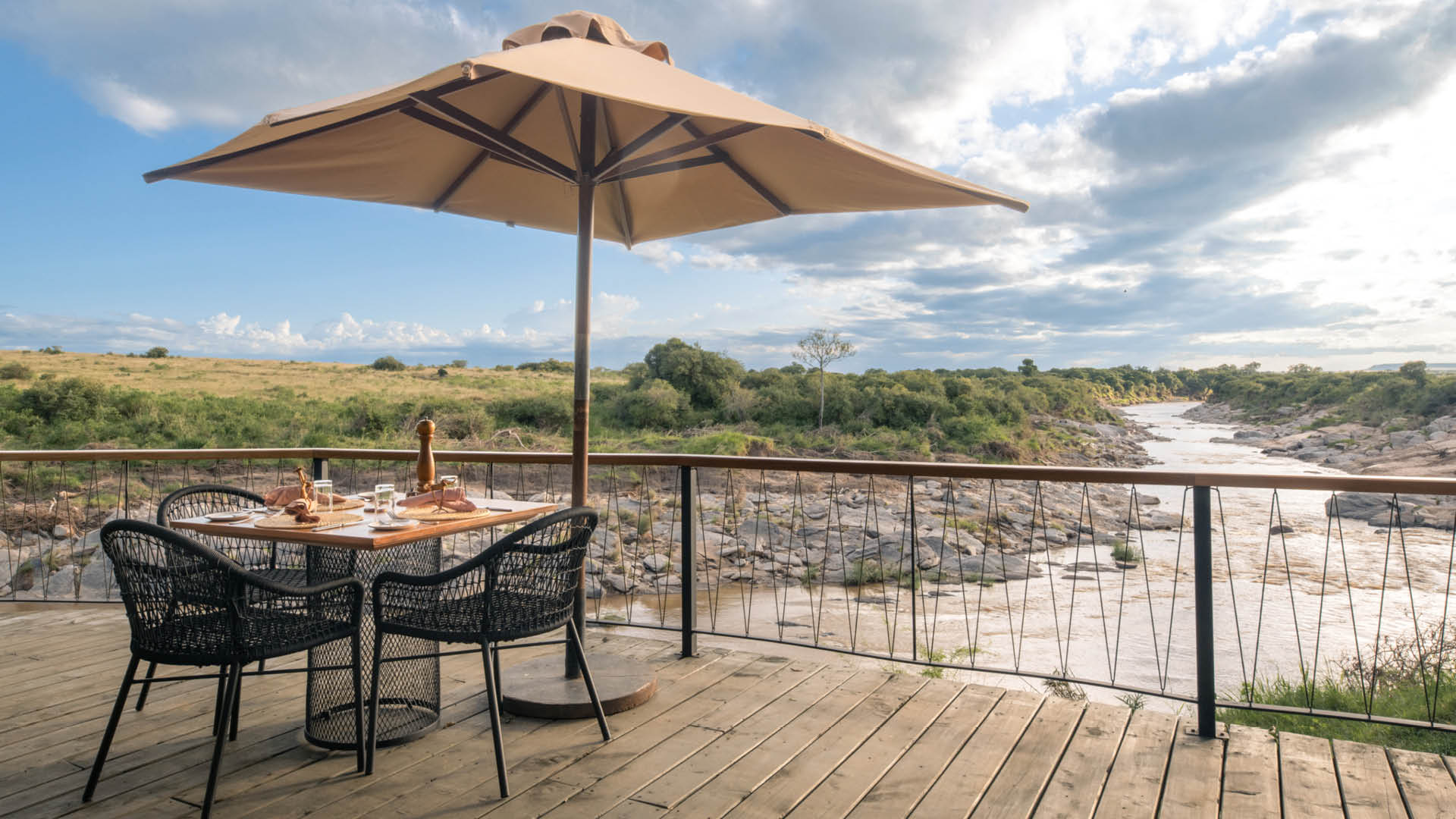A table is set on the deck with a view of the river