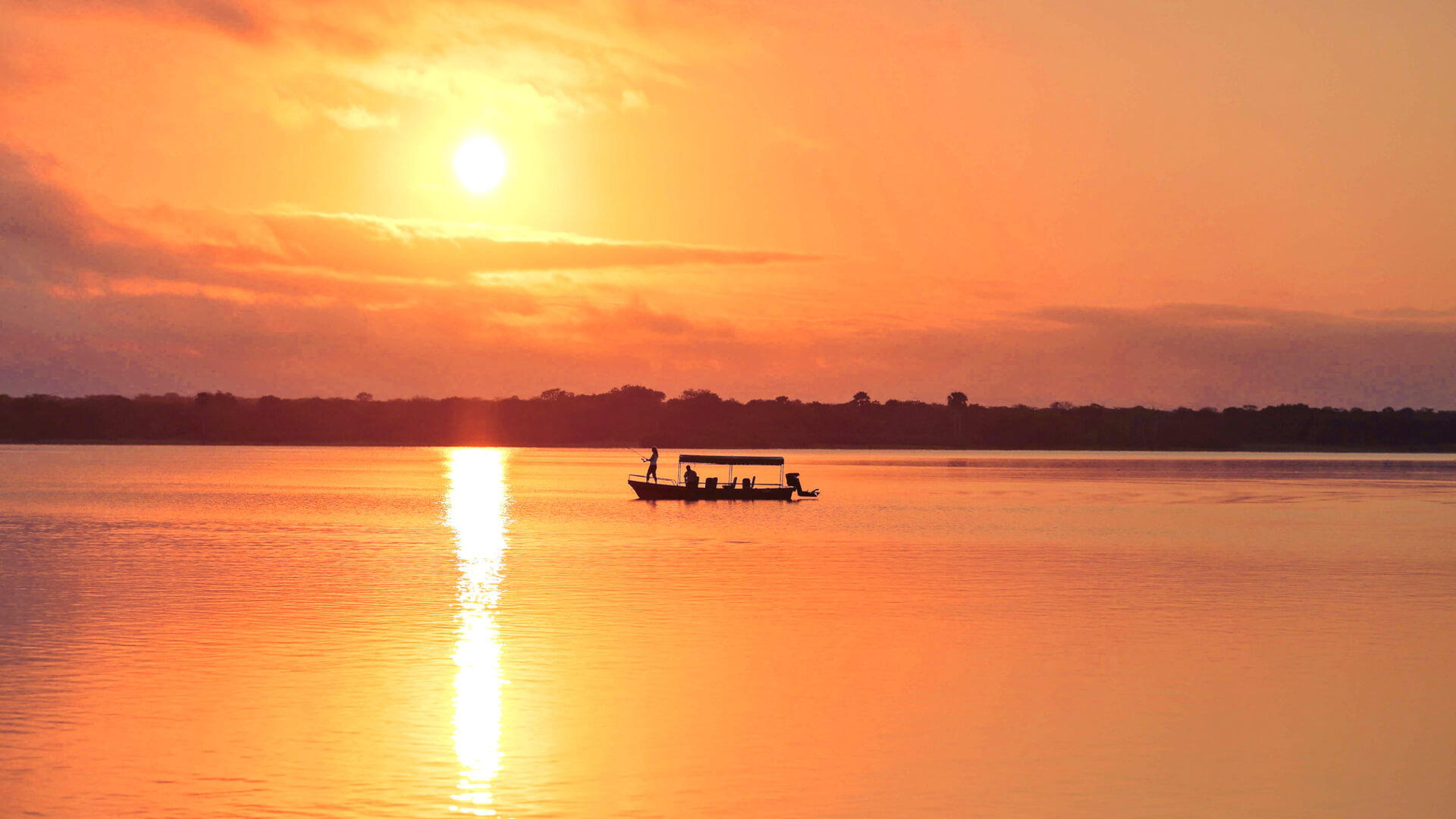 A boat on the lake at sunset while guests enjoy a fishing safari