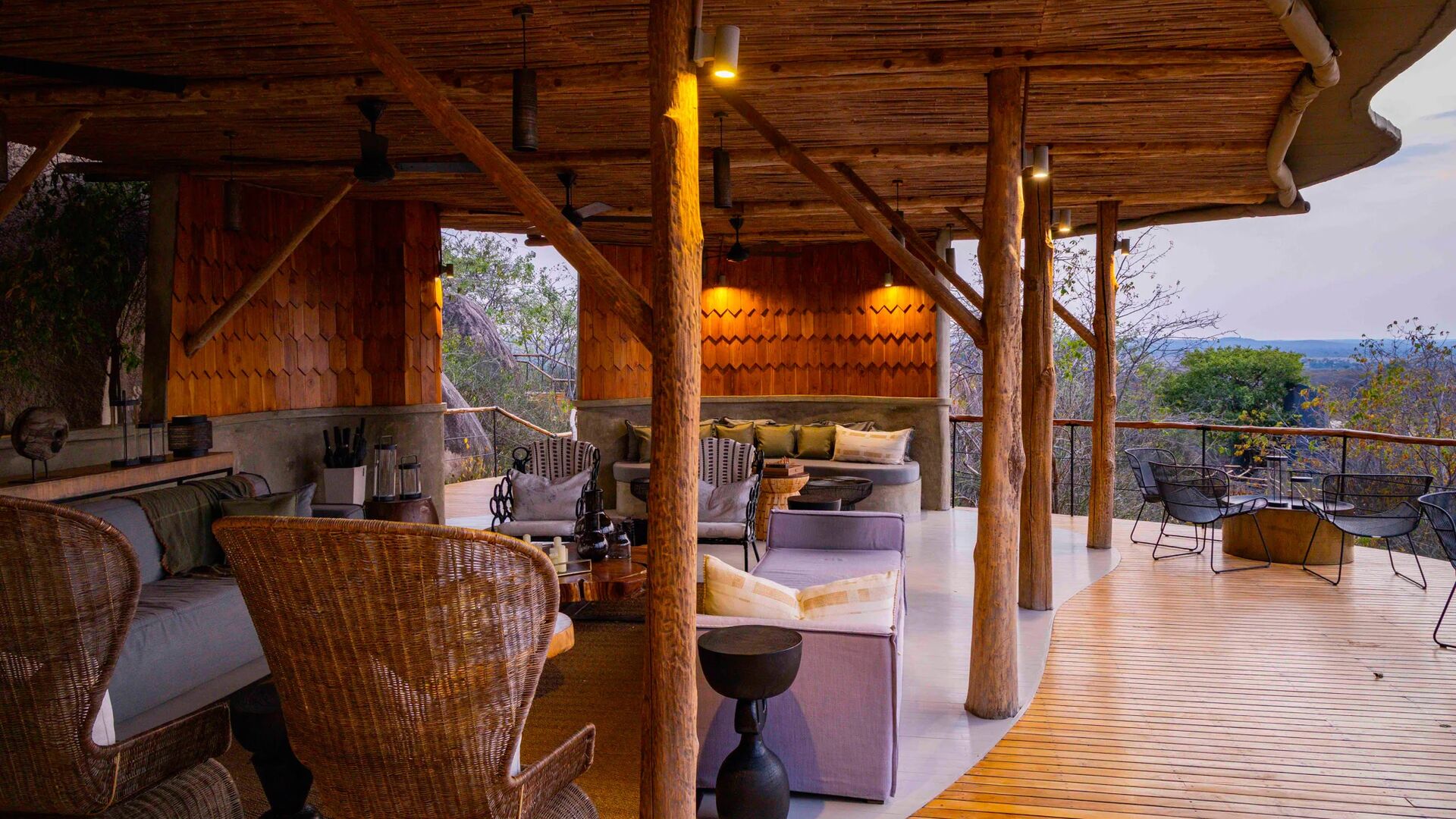 An open-air lodge lounge blending natural timber, warm lighting, and sweeping views over the wilderness