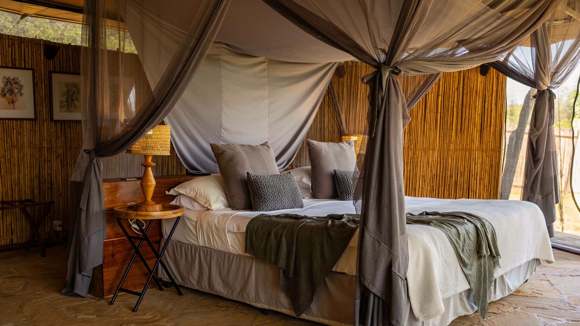 A spacious safari tent at Roho ya Selous with a canopy bed, wooden furnishings, and neutral decor