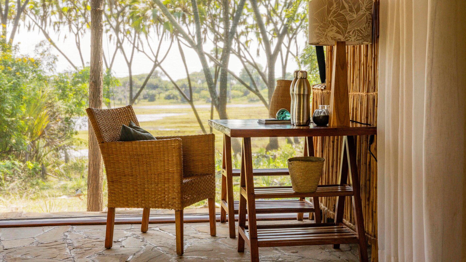 A desk and chair inside a guest tent at Roho ya Selous facing a river view through a window