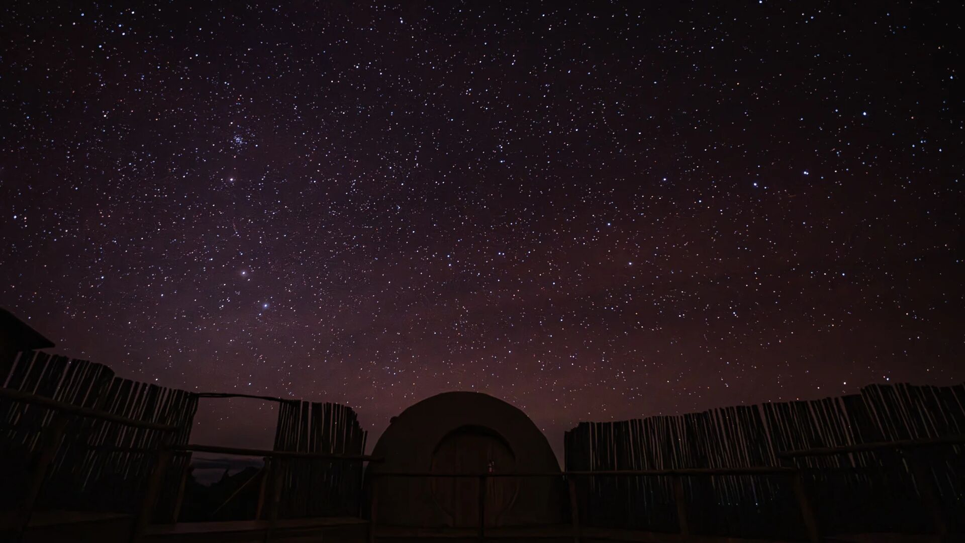 A silhouette of The Highlands Camp inn Africa against a dark starry sky.