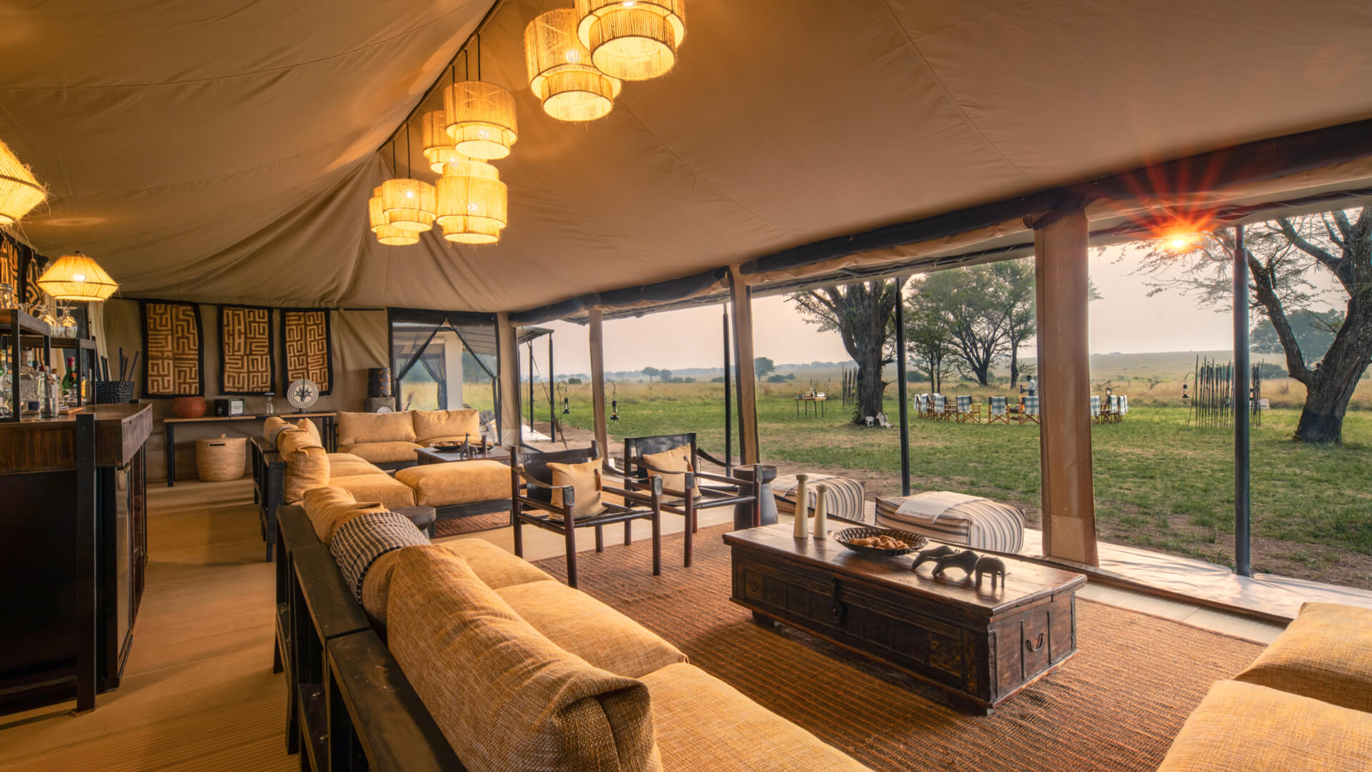 A gently lit and cosy lounge looks out from its tented structure onto the bush