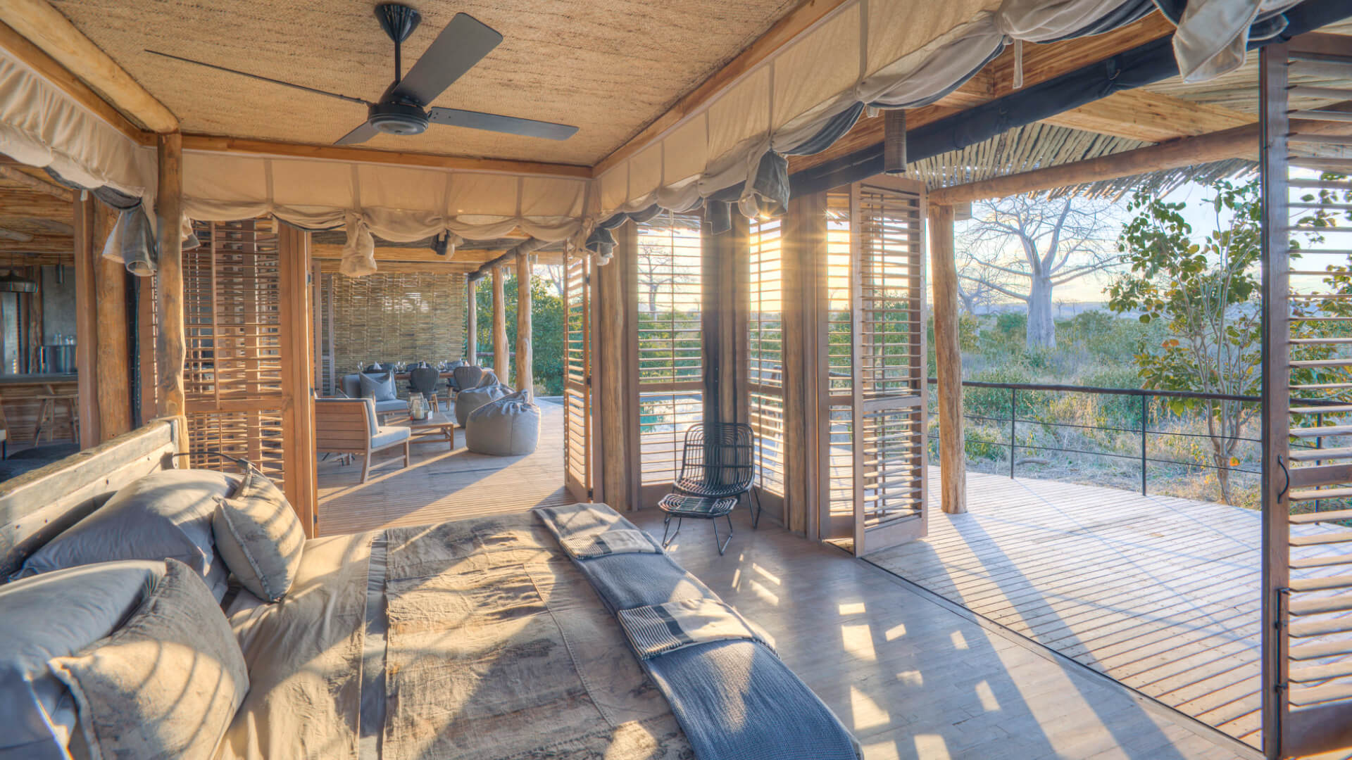 Jabali Private House, Ruaha National Park, double room interior with double bed with pillows and throw blanket, shutters open to the deck and main area, chair in the corner