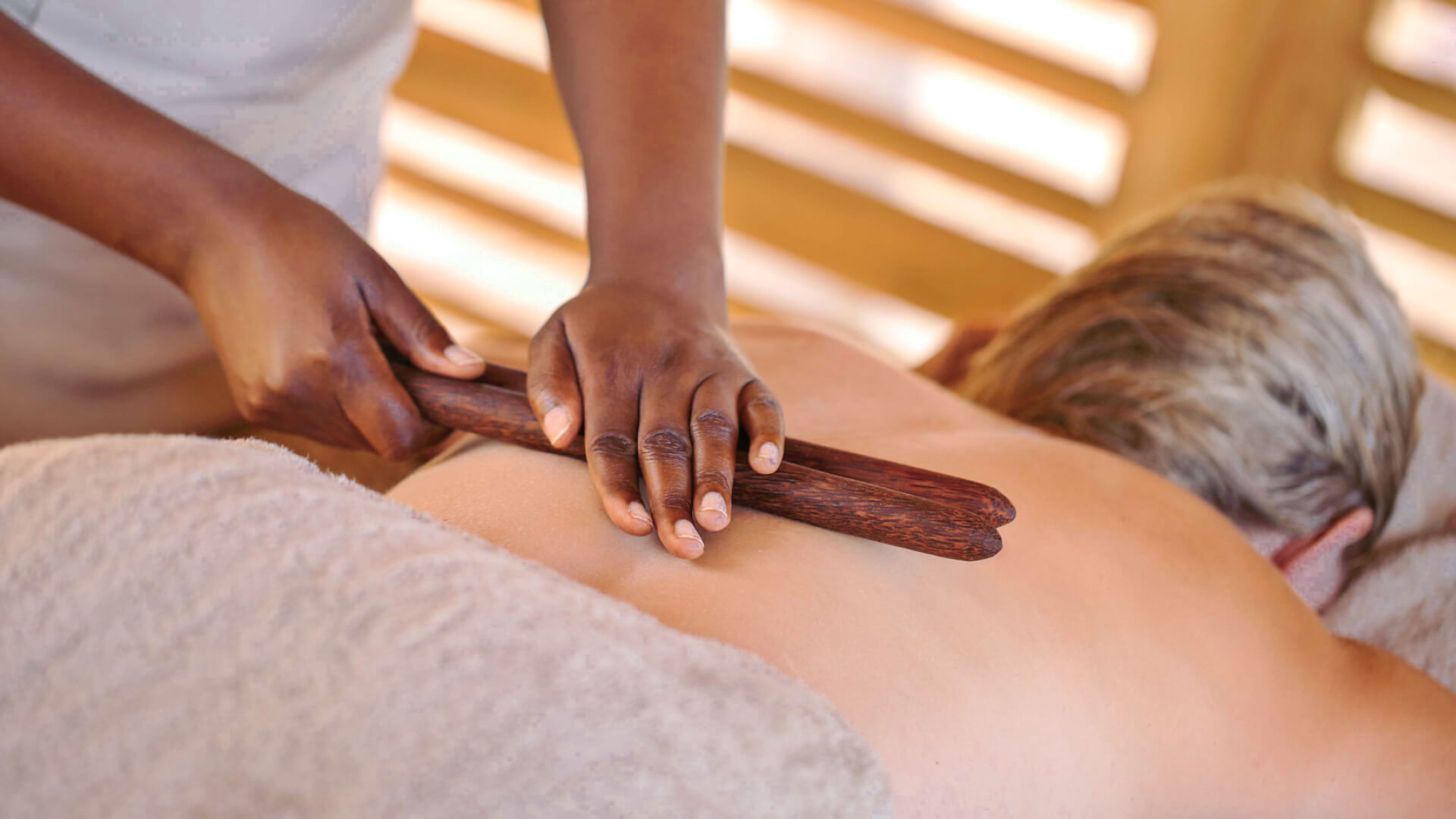 Jabali Private House, Ruaha National Park, Spa treatment for guest, therapist using two sticks across guest's back with her hands