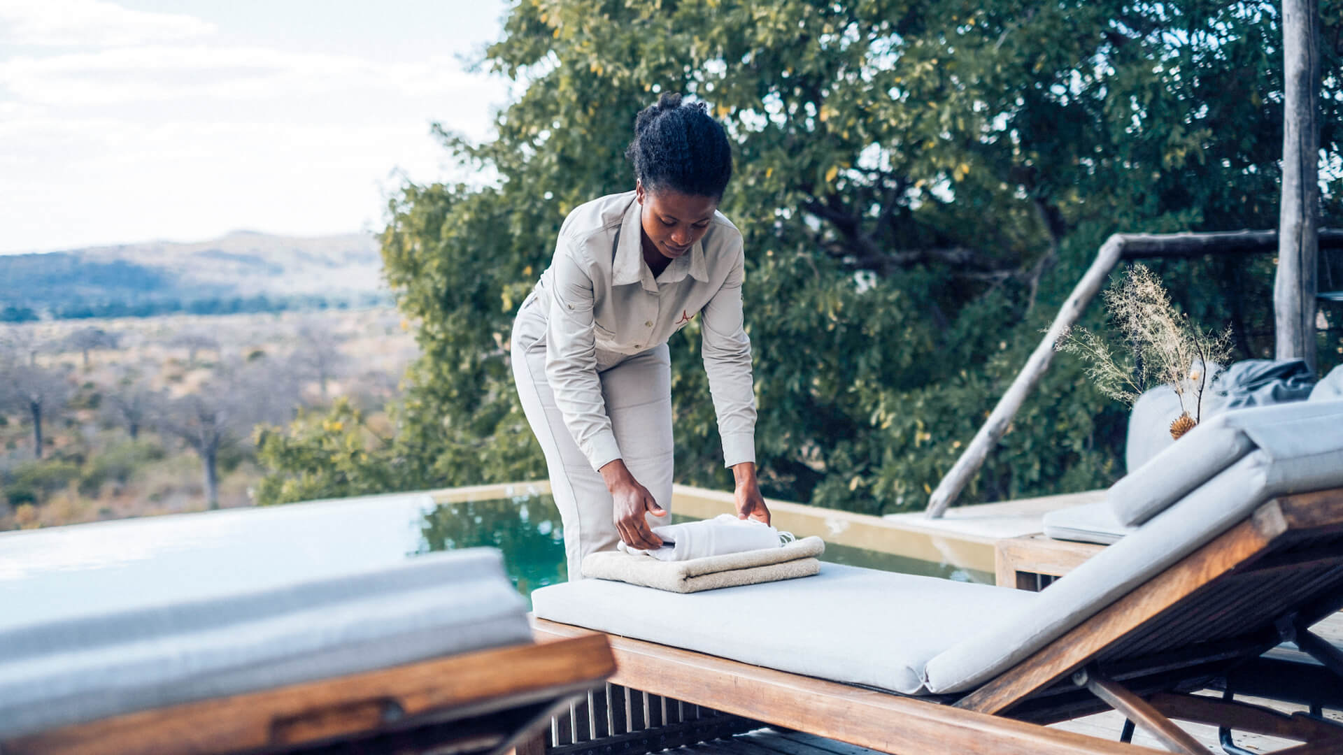 Jabali Ridge, Ruaha National Park, camp staff placing folded towels on the lounger by the pool