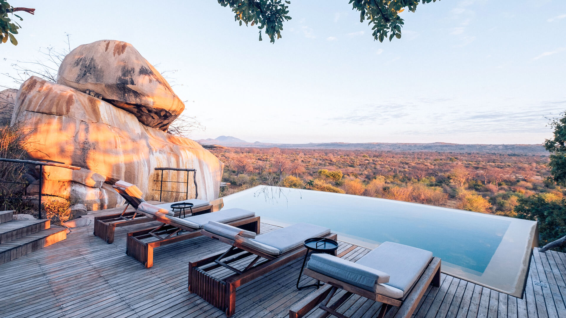Jabali Ridge, Ruaha National Park, loungers at the pool next to boulder, view of the park in the background