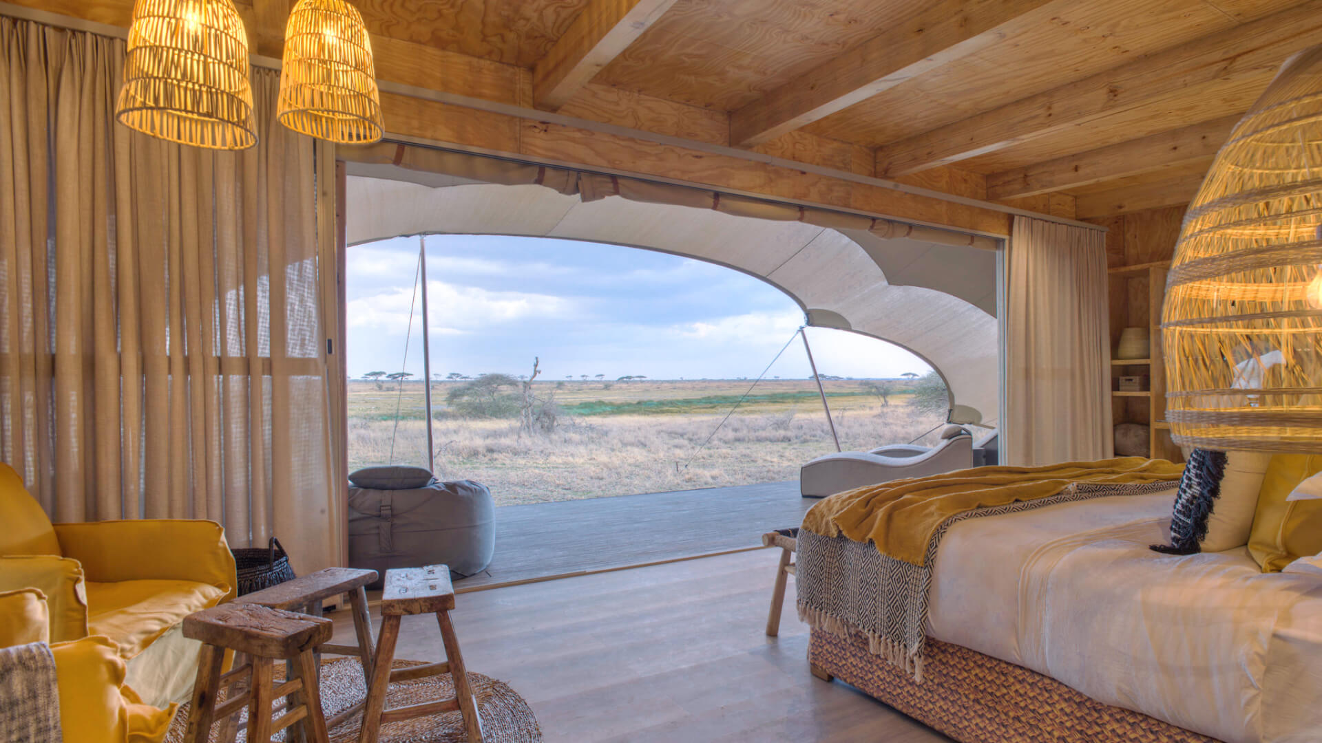 Namiri Plains, Serengeti National Park, guest tent interior, hanging lights, couches, bed made, curtains drawn and doors open