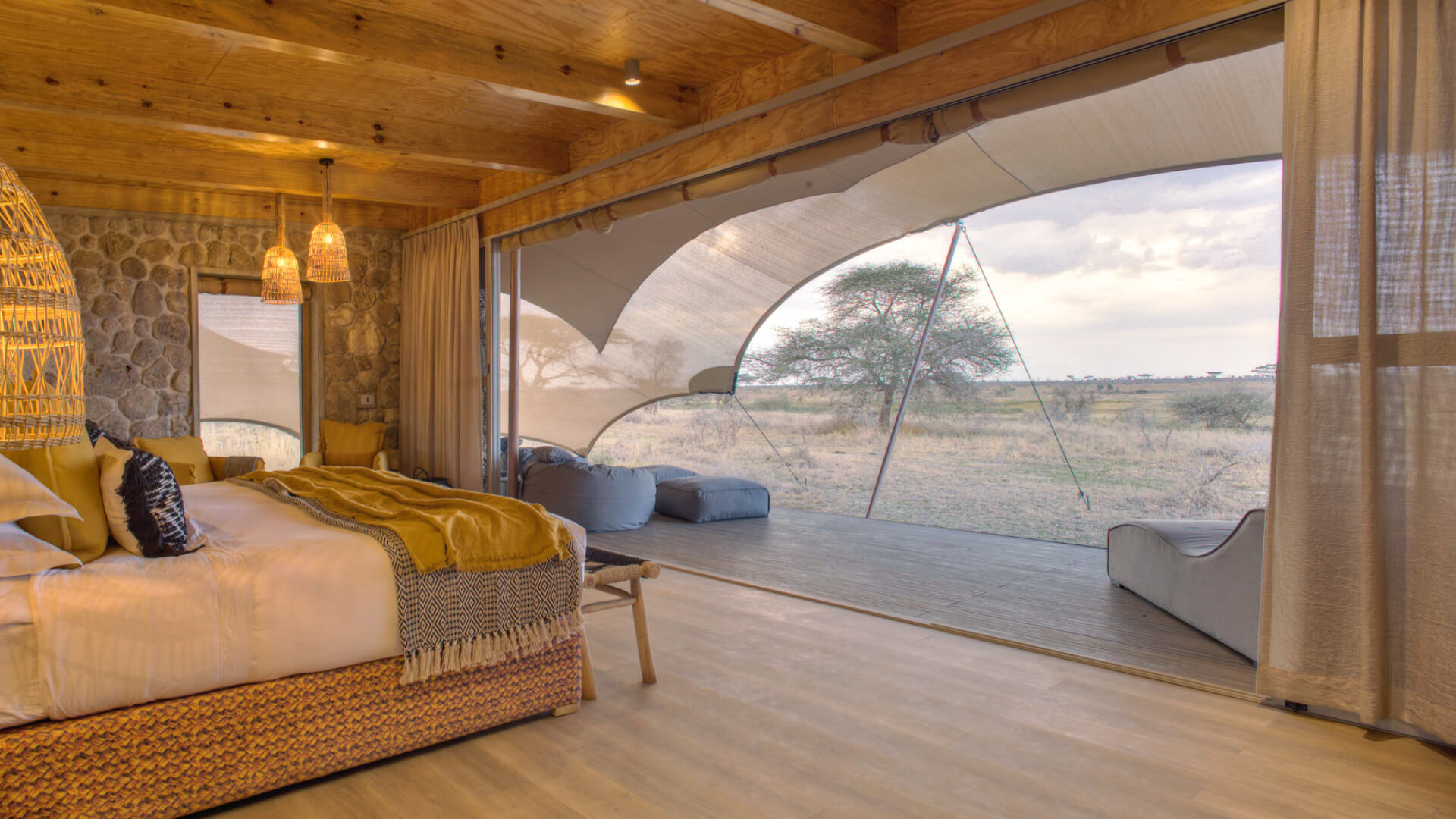 Namiri Plains, Serengeti National Park, guest tent interior, hanging lights, couches, bed made, curtains drawn and doors open