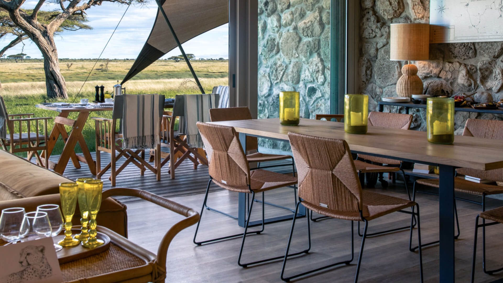 Namiri Plains Retreat, Serengeti National Park, dining table with shanga vases and wicker chairs, lamp on the side table with breakfast setup