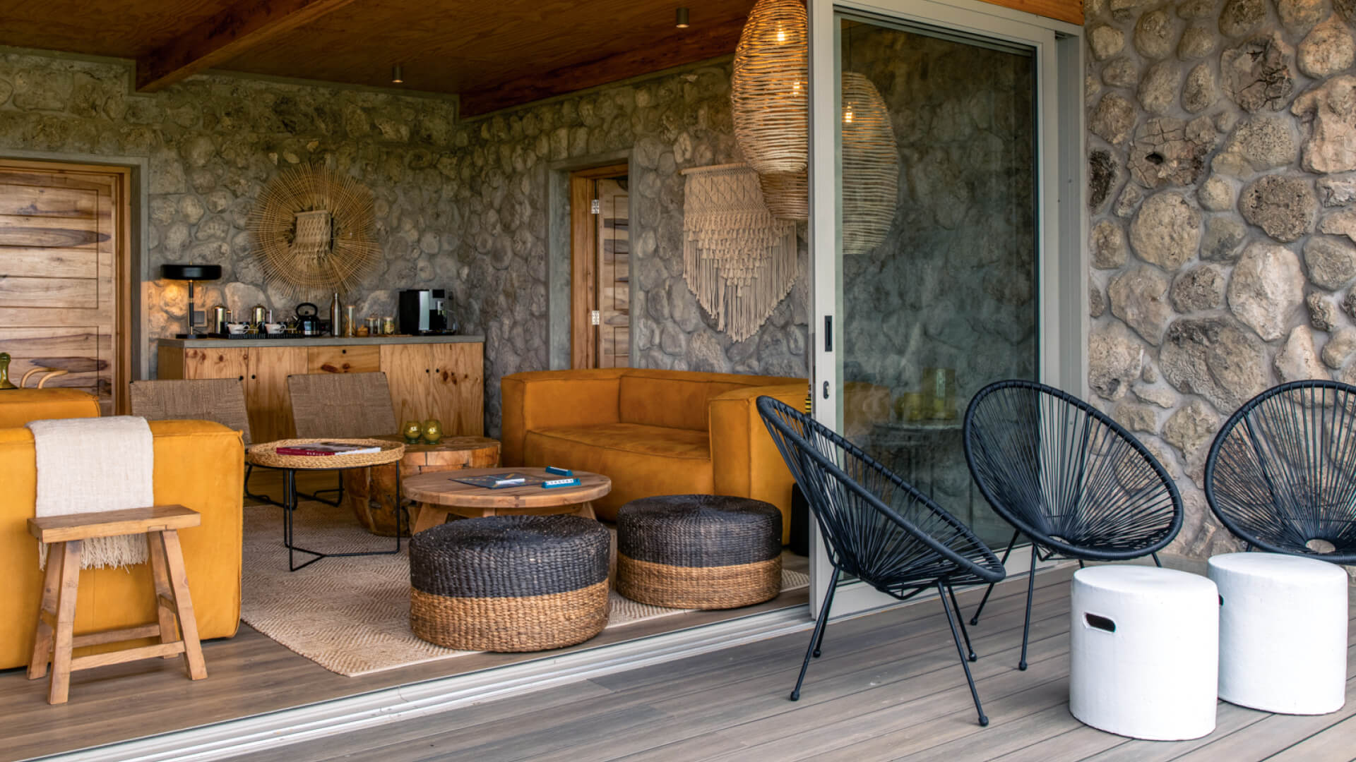 Asilia Namiri Plains Retreat, lounge area interior with couches, chairs, tables with books and scrabble, coffee station in the back, chairs and tables on the deck