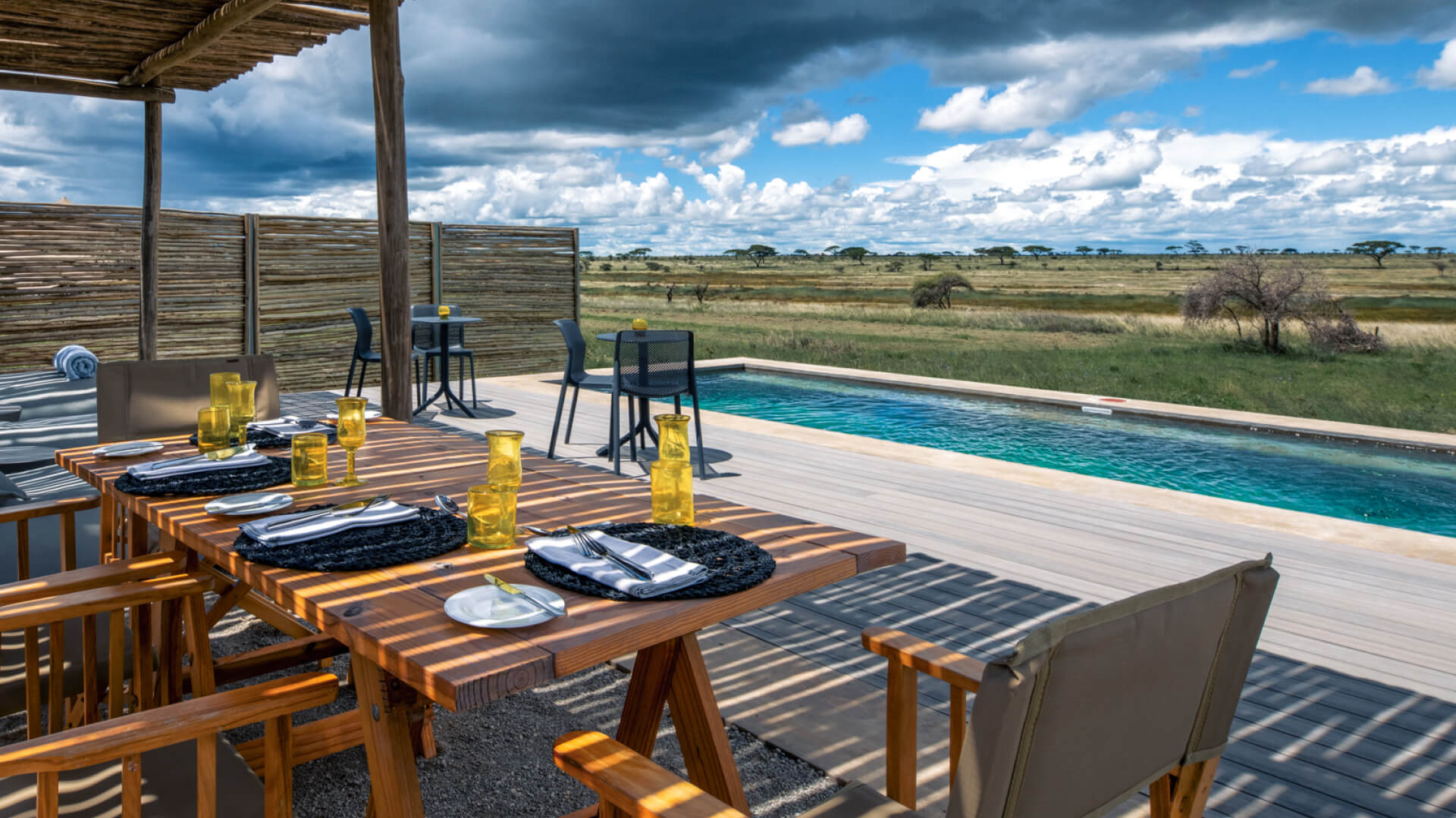 Namiri Plains Retreat, Serengeti National Park, lunch setup at the pool, table and chairs on the deck, placemats and shanga glasses on the table