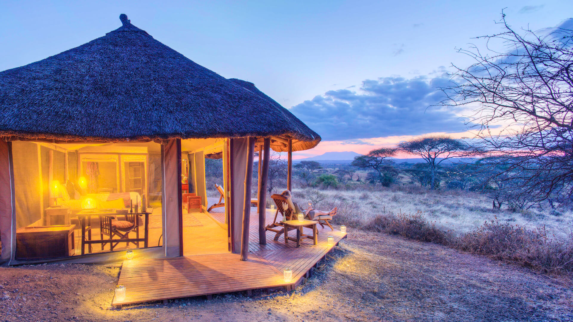 Outside view of guest tent, guest on the deck, olivers camp, Tarangire National Park, Tanzania