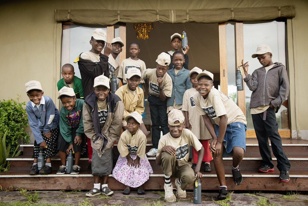 A group of young children wearing Porini t-shirts stand for a photo