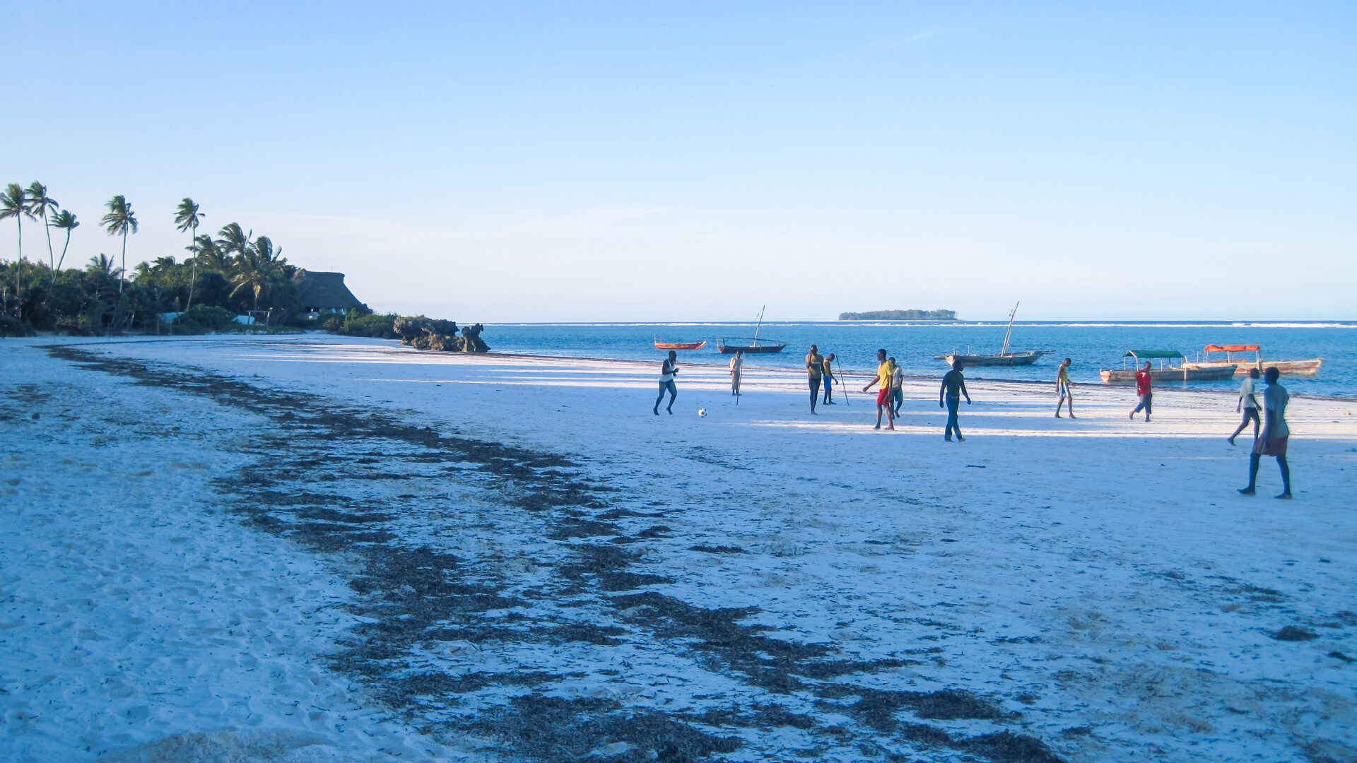 People walking along the white sand beach in zanzibar