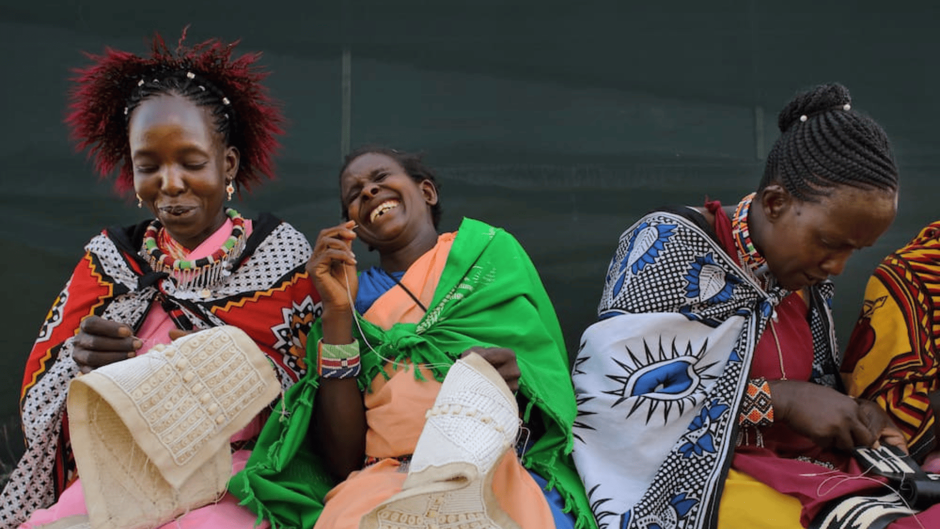 maasai ladies sewing beads sat laughing together, east africa, the maa trust
