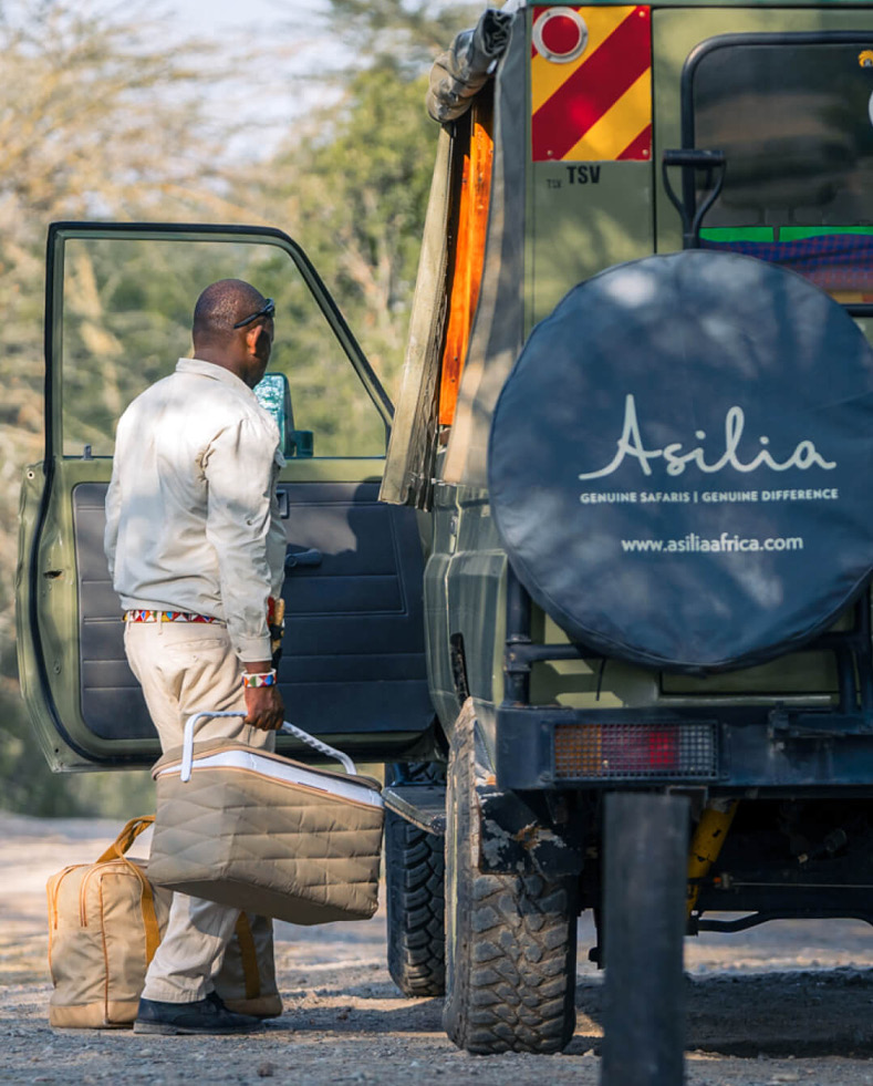 Male staff putting a picnic into a safari vehicle at Ol Pejeta Bush Camp in Kenya
