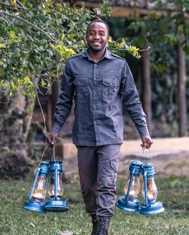male staff member smiling, carrying night lamps, rubondo island, tanzania, asilia africa