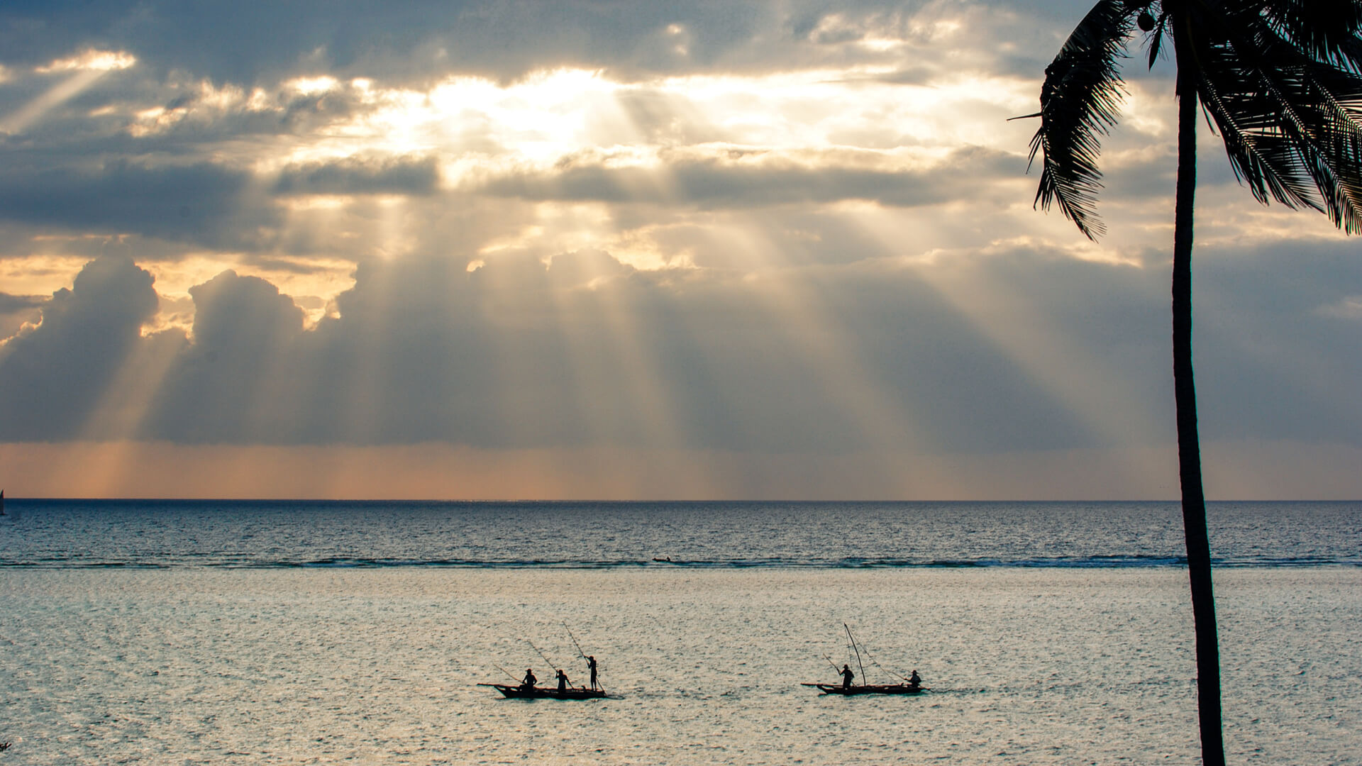 Two small fishing boats pass close to the shore in the early morning